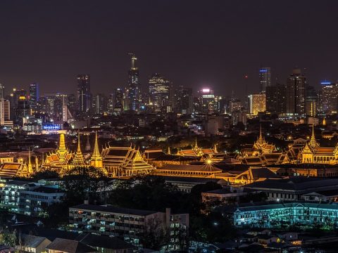 Panoramablick auf das nächtliche Bangkok mit der von bunten Lichtern erleuchteten Skyline der Stadt, mit hoch aufragenden Wolkenkratzern und belebten Straßen.