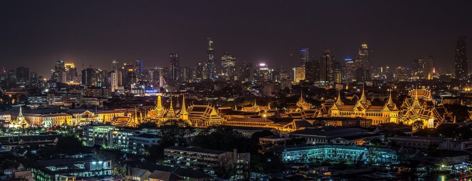 Panoramablick auf das nächtliche Bangkok mit der von bunten Lichtern erleuchteten Skyline der Stadt, mit hoch aufragenden Wolkenkratzern und belebten Straßen.